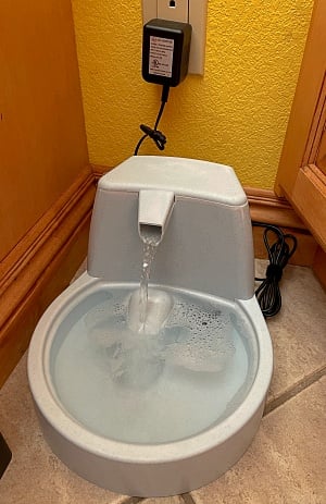 Here's my cats water fountain. It needs an outlet to power the pump, the cord is plugged in above it. It has a spout where the water splashes into the bowl.   They have fresh water all the time and it makes a nice relaxing sound.